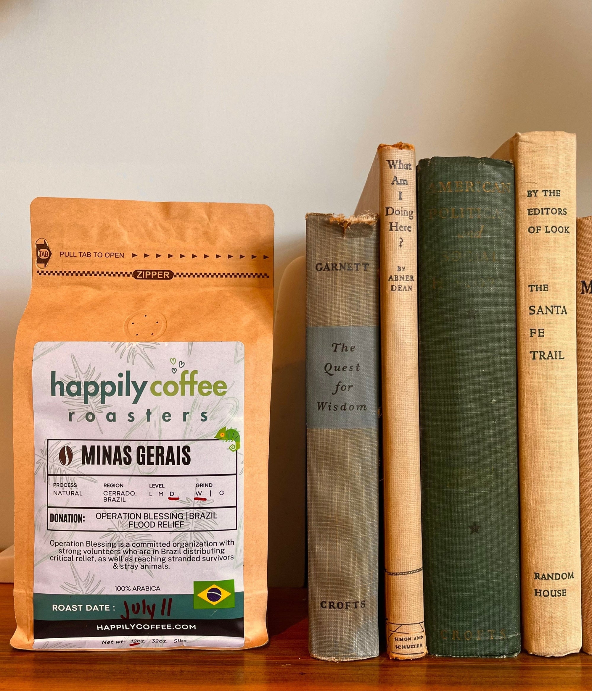 Happily Coffee Roasters package with vintage books on a wooden surface