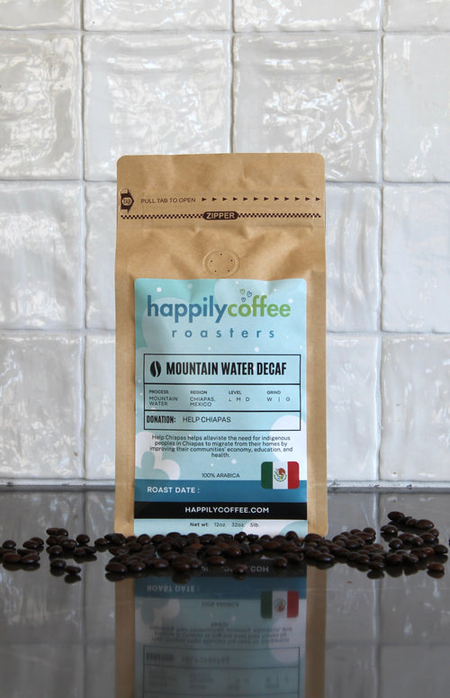 Happily Coffee Roasters mountain water decaf package with coffee beans on a reflective surface and tiled wall background