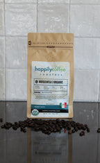 Happily Coffee package with coffee beans on a tiled floor